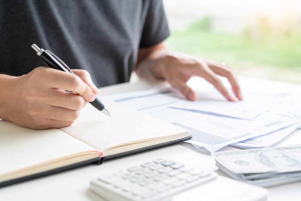 Stressed man calculating accounting holding a receipt checking bills, taxes, bank account.