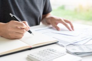 Stressed man calculating accounting holding a receipt checking bills, taxes, bank account.