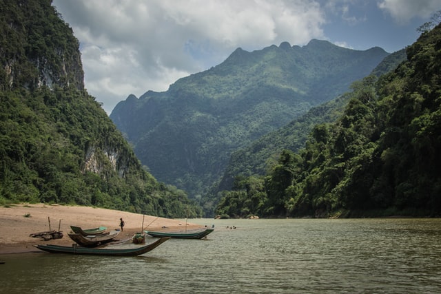 Scenery of Laos mountains and a lake with boats. Laos can be visited on a budget.