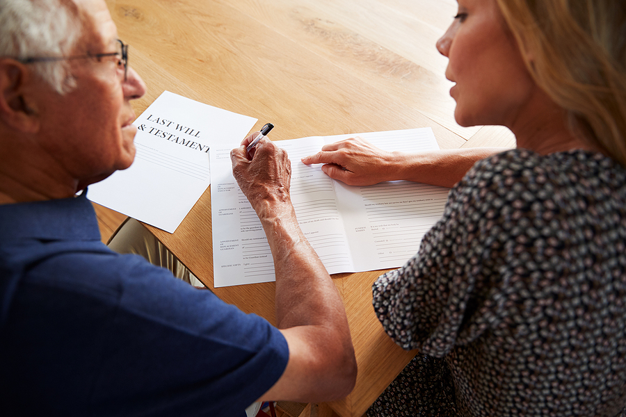 Woman helping a senior man complete his last will and testament