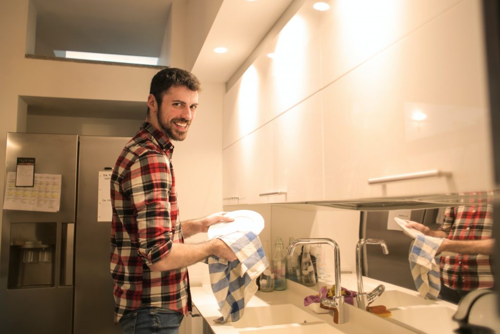 Man while cleaning a plate in the kitchen