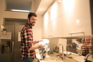 Man while cleaning a plate in the kitchen