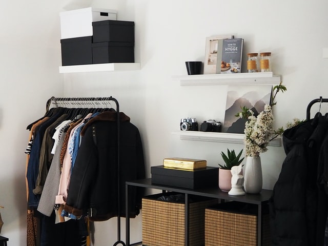 A capsule wardrobe in a bedroom next to a shelf of items. It has been created on a budget.