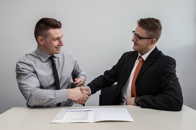 Two men shaking hands as they have been hired for a business that was previously struggling with staff.