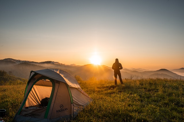 A man watching the sunrise with the tent he hired to see Australia.